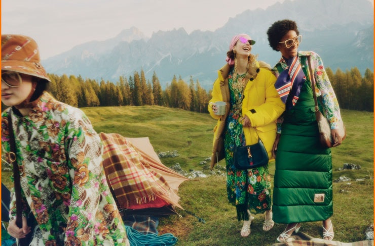 Three people dressed in The North Face x Gucci on a grassy hill.